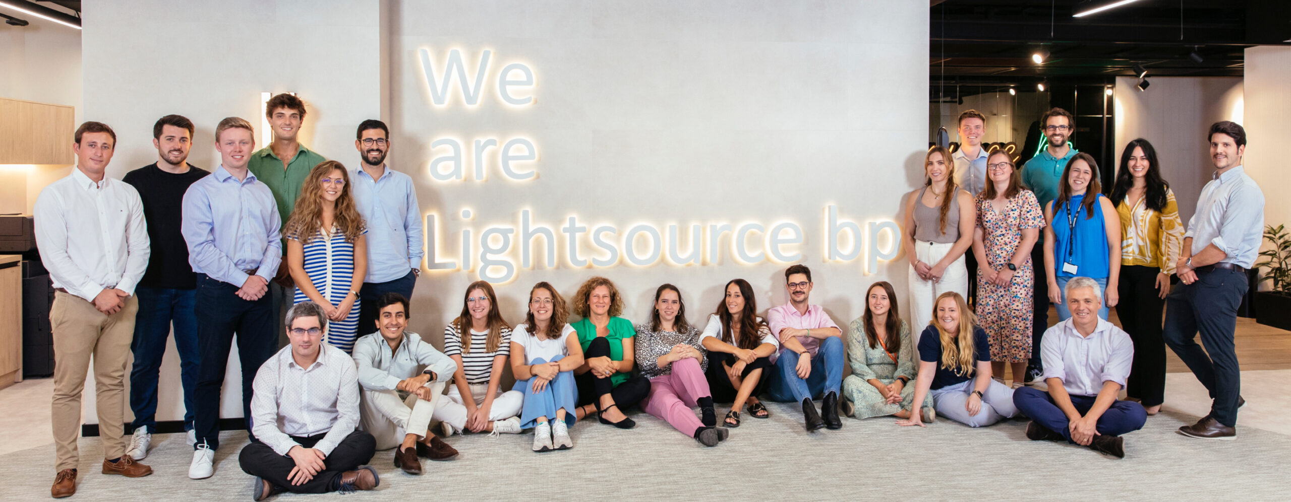 Lightsource bp team members posing in front of a sign saying 