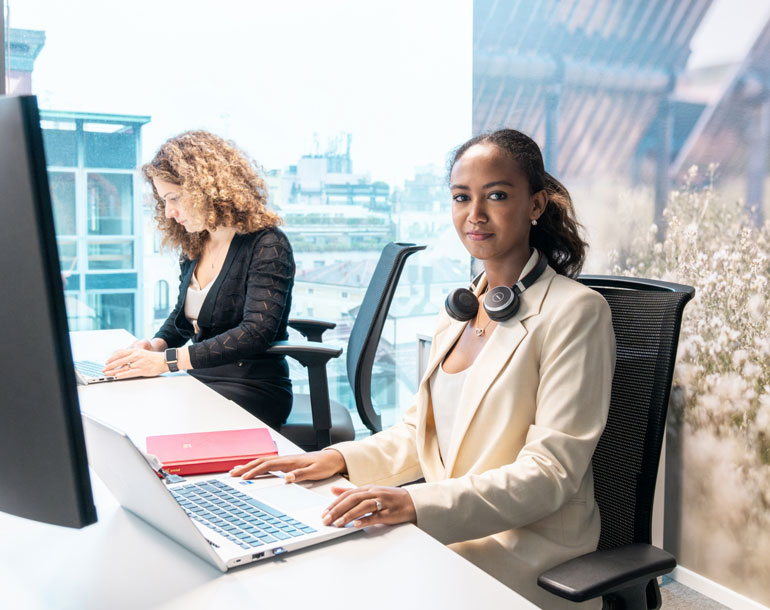 Two female office workers working by their desks