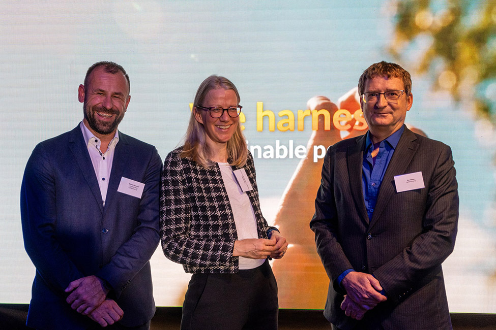 Three people, two men and a woman smiling and posing for a photo.